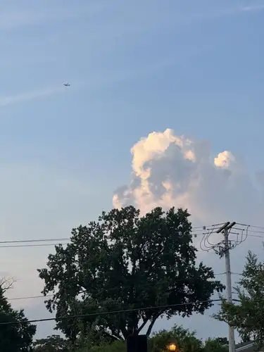 Towering clouds meet a distant plane in the evening glow.